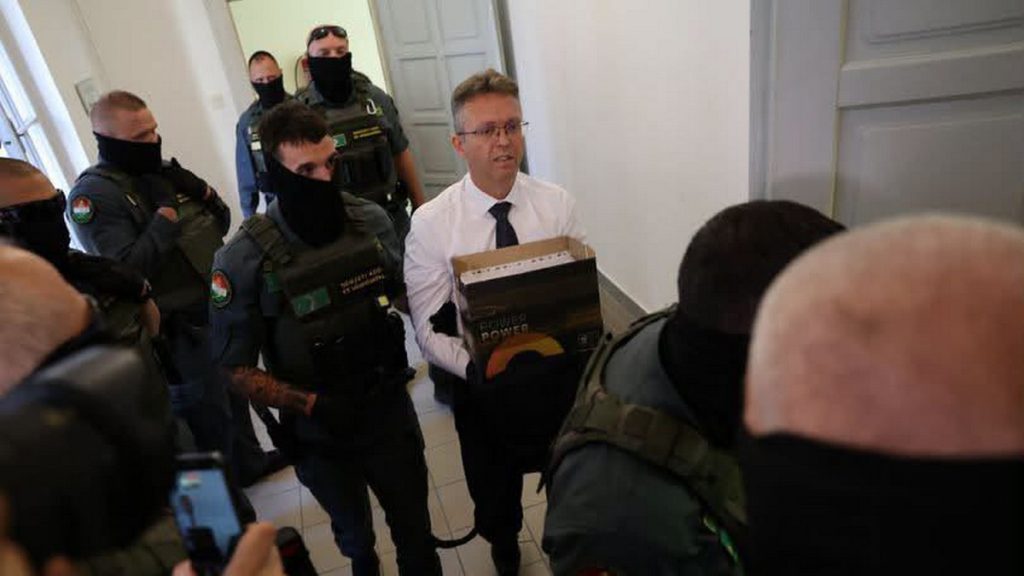Miközben Hankó Balázs letartóztatásáról döntöttek, a NAV a családi házánál tartott házkutatást Hankó Balázst vezetőszárral kísérik a bíróság épületében